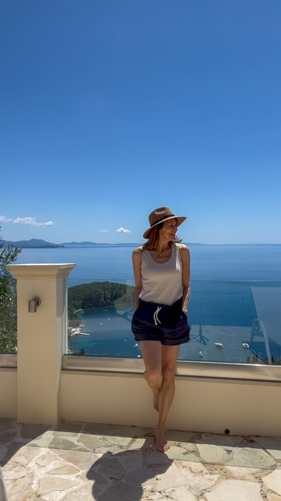 Nancy, the author, standing on the terrace of Villa Bliss with sea views and blue sky in background. Copyright@2025 NancyRoberts