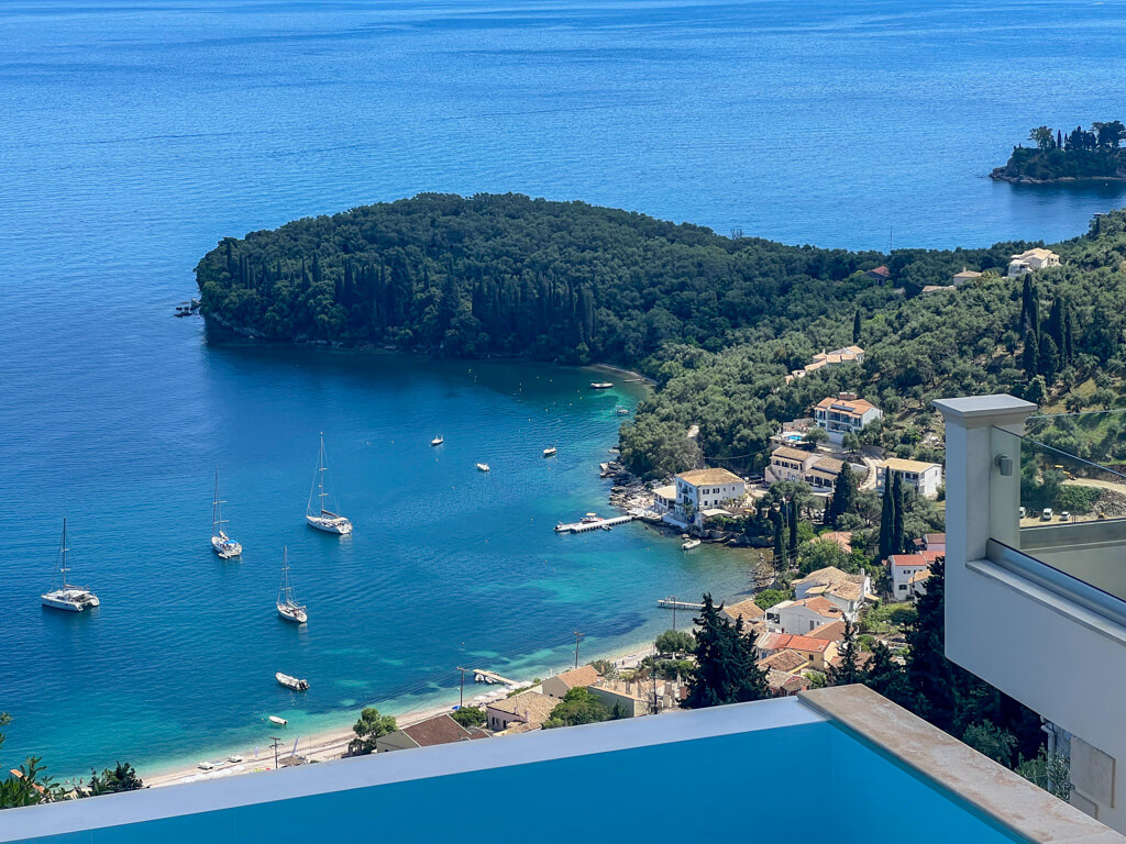 Villa Bliss view of Kalami bay Corful Showing brilliant blue sea, yachts at anchor and forested headland with small village around bay. Copyright@2025NancyRoberts