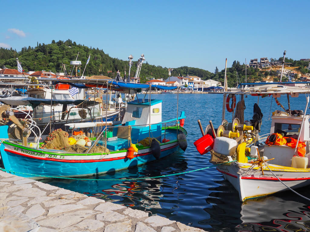 Sivota Greece waterfront with colourful painted wooden fishing boats tied up at the quayside. Copyright@2025 NancyRoberts