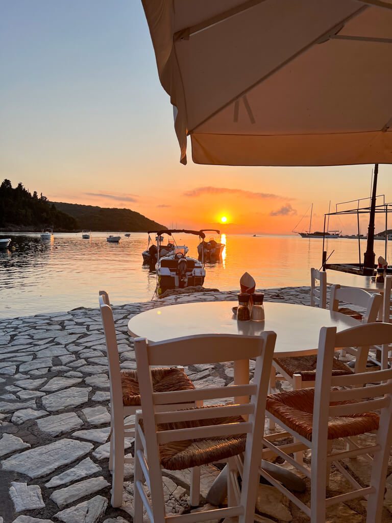 View of sun setting over Sivota bay from a taverna table on the waterfront. Copyright@2025 NancyRoberts