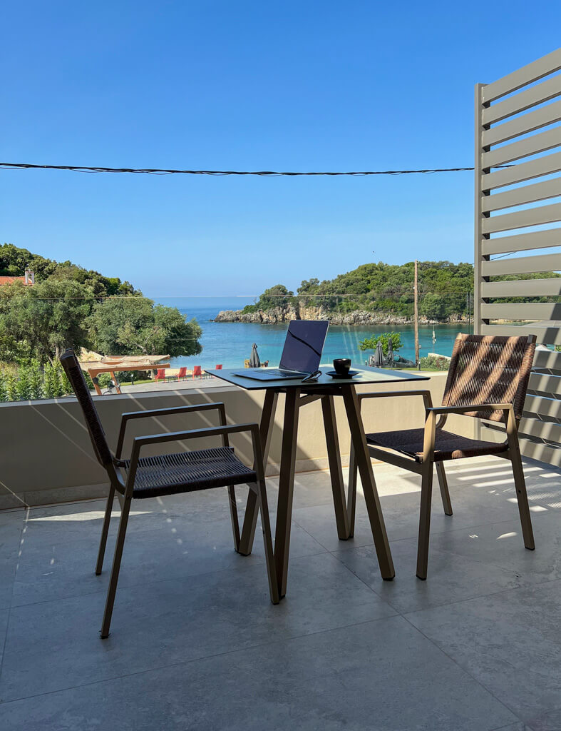 Laptop and cup of coffee on table on balcony of the hotel suite with sea in background. Copyright@2025 NancyRoberts