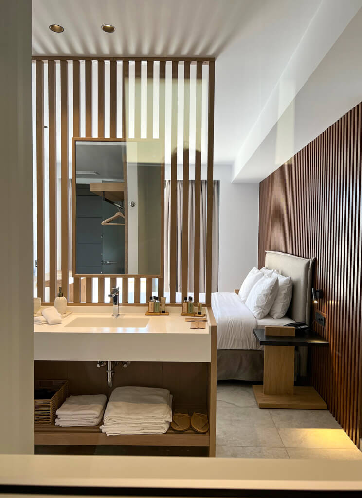 Interior of suite showing washstand with toiletries and bedhead in background. Copyright@2025 NancyRoberts