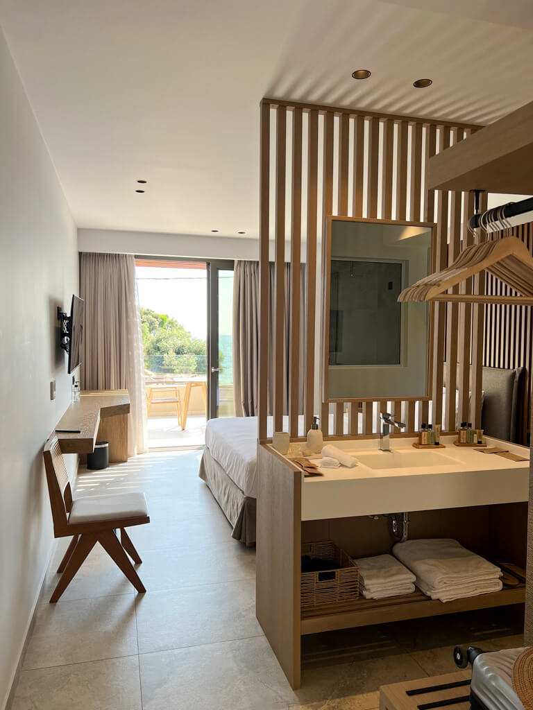 Interior of suite at Arete Lifestyle Hotel, Sivota Greece. Contemporary washstand acts as room divider, sliding door opens to balcony and sea view. Copyright@2025 NancyRoberts