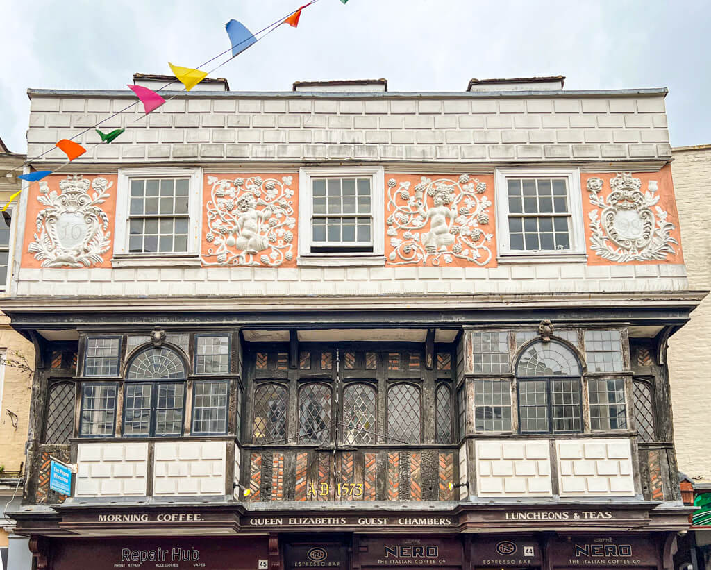 A richly decorated facade of a medieval buikding in Canterbury with wooden windows and carved embellishments. Copyright@2025 Nancy Roberts